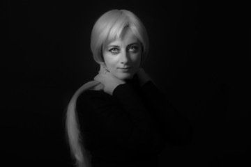 Photo shooting indoors. On a black background. A woman with long white hair, wearing a black...