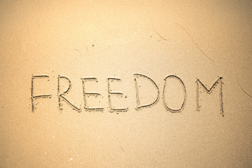 Freedom word is written on the beach sand