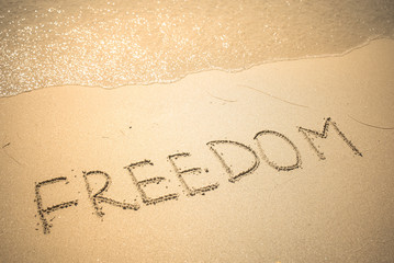 Freedom word is written on the beach sand