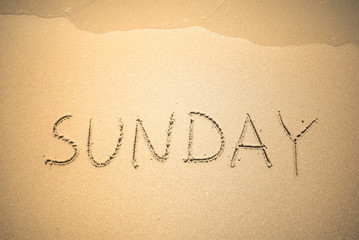 Fototapeta na wymiar Sunday word is written on the beach sand