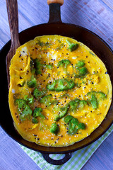 Omelette with broccoli, herbs and sesame seeds in frying pan