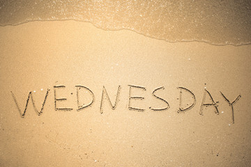 Wednesday word is written on the beach sand