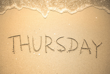 Fototapeta premium Thursday word is written on the beach sand