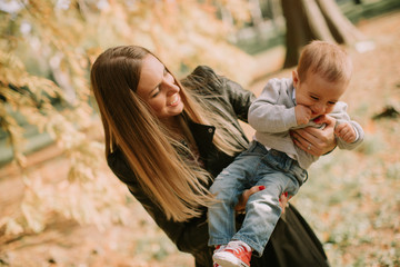 Fototapeta na wymiar Mother and baby boy having fun in autumn park