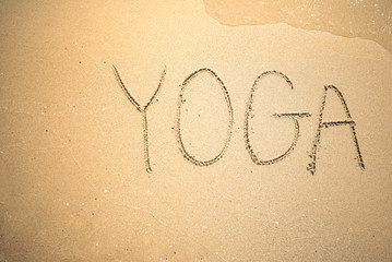 Yoga word is written on the beach sand