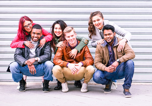 Happy multiracial group of best friends portrait on grey wall background at winter time - Different culture teamwork students huddled together posing photo outdoors for integration and peace concept