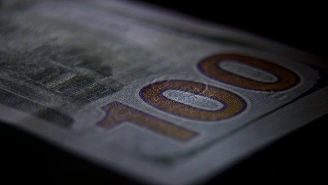 Elements and signs on a 100 banknote: a portrait of the president, a figure of par value. Scanning a banknote with ultraviolet light: a green beam moves along the banknote. Check for counterfeit bill