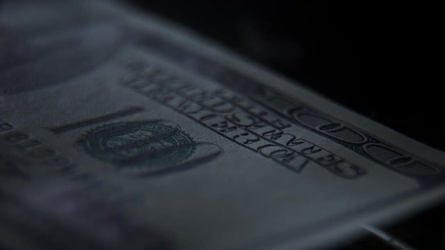 Elements and signs on a 100 banknote: a portrait of the president, a figure of par value. Scanning a banknote with ultraviolet light: a green beam moves along the banknote. Check for counterfeit bill