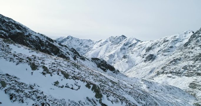 Backward aerial over winter snowy mountain pass with mountaineering skier people walking up climbing.snow covered mountains top and ice glacier.Winter wild nature outdoor establisher.4k drone flight