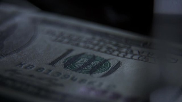 Elements and signs on a 100 banknote: a portrait of the president, a figure of par value. Scanning a banknote with ultraviolet light: a green beam moves along the banknote. Check for counterfeit bill