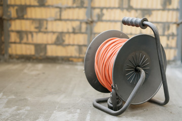 Orange power extension cable reel at the construction site
