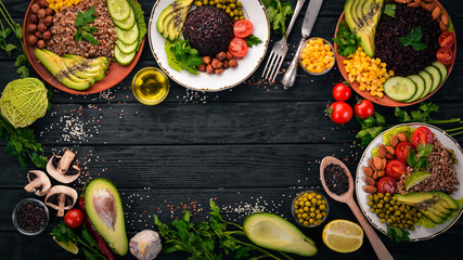 Healthy food. Black rice, buckwheat, avocado, cherry tomatoes, green peas and hazelnut. On a wooden background. Top view. Free space for your text.