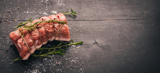 Raw meat Beef fillet with rosemary and spices on a black wooden background. Top view. Free space...
