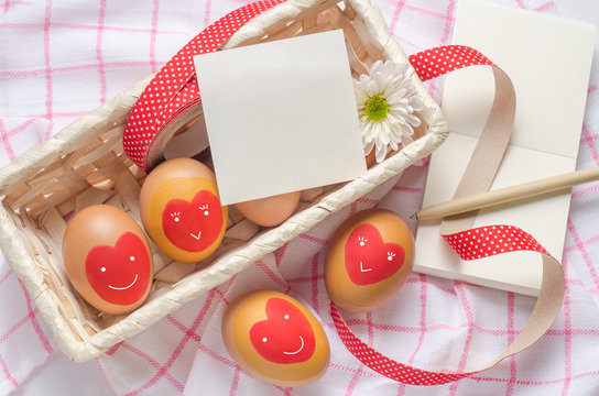 White paper note and egg with red heart on basket