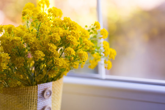 Lush yellow bouquet of little tender flowers near window