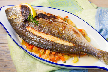 Whole dorado or dorada fish with vegetables, thyme and lemon. View from above, top, horizontal