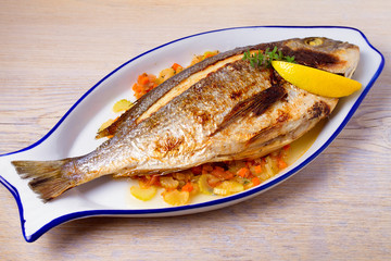 Whole dorado or dorada fish with vegetables, thyme and lemon, horizontal