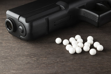 Balls and a gun for playing airsoft on a dark background.