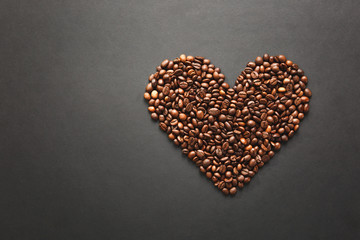 Brown coffee beans in form of heart isolated on black texture background for design. Saint Valentine's Day card on fabruary 14, holiday concept.