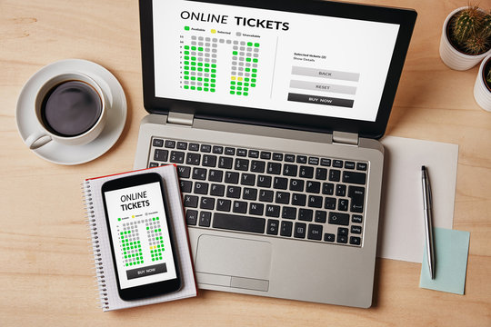 Online tickets concept on laptop and smartphone screen over wooden table. All screen content is designed by me. Flat lay