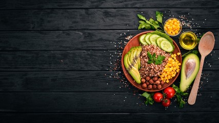 Healthy food. Buckwheat, avocado, cucumber, corn and hazelnut. On a wooden background. Top view....