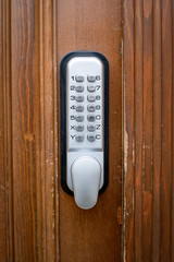 Silver color code key on brown wooden door.