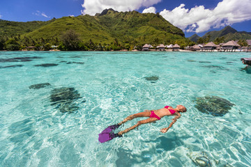 Luxury paradise travel vacation bikini woman relaxing snorkeling in idyllic ocean coral reefs at...