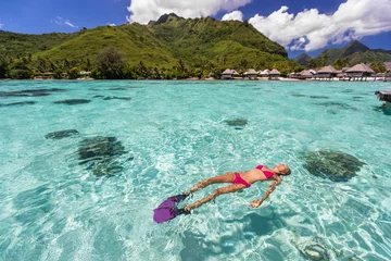 Foto auf Leinwand Luxury paradise travel vacation bikini woman relaxing snorkeling in idyllic ocean coral reefs at luxury overwater bungalows resort in Tahiti. French polynesia cruise lifestyle. Holiday girl getaway. © Maridav