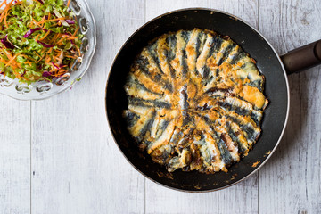 Fresh Fried Sardines in Pan with Salad on Wooden Surface.