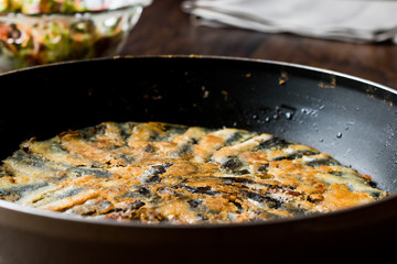 Fresh Fried Sardines in Pan with Salad on Wooden Surface.