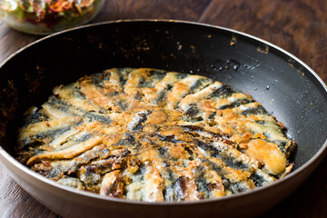 Fresh Fried Sardines in Pan with Salad on Wooden Surface.