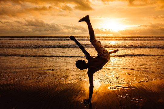 Rapaz a brincar ao p&ocirc;r-do-sol na praia de F&uacute;tila em Cabinda, Angola