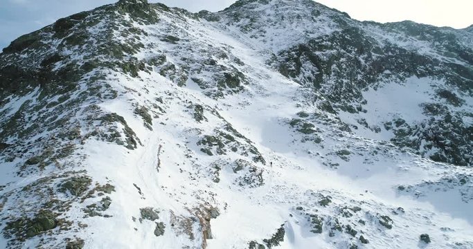 Side aerial over winter snowy mountain with mountaineering skier people walking up climbing.snow covered mountains top and ice glacier.Winter wild nature outdoor establisher.4k drone flight