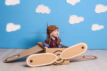 Obraz premium Little child girl in a pilot's costume is playing and dreaming of flying over the clouds.