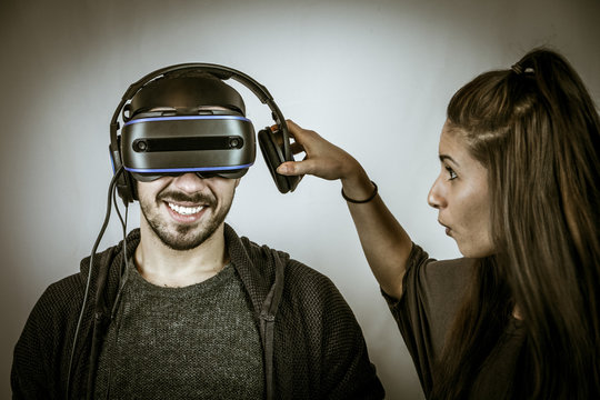 Junger Mann spielt mit Virtual Reality Datenbrille, Freundin beschwert sich (Look)