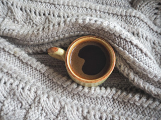 Winter coffee. Cup of black coffee in a knitted sweater.
