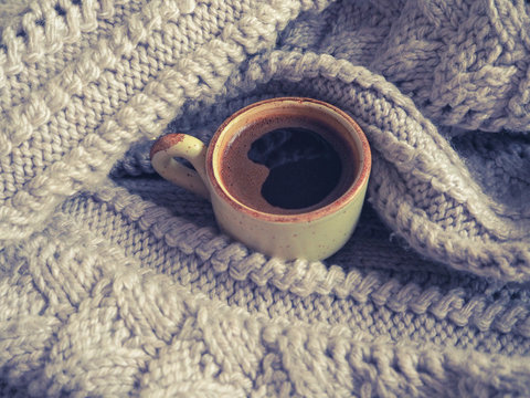 Winter coffee. Cup of black coffee in a knitted sweater.
