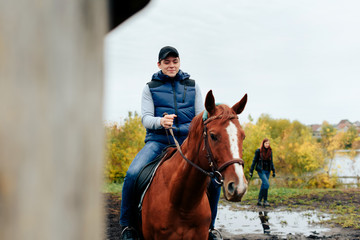Fototapeta premium man learns riding a horse in autumn in a rural landscape