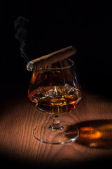 smoked cigar on a glass of cognac