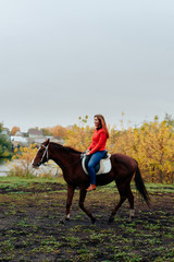 beautiful girl rides a horse in a village in the fall