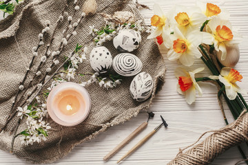 modern easter eggs on rustic background with fresh spring flowers and daffodils top view. happy easter greeting card. stylish painted eggs. easter flat lay for instagram or blog