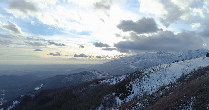 Forward aerial top view over winter snowy mountain and woods forest at sunset or sunrise.Blue hour dusk or dawn twilight Alps mountains snow season establisher.4k drone flight establishing shot