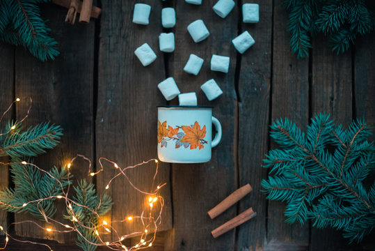 White cup with marshmallow on a wooden background.