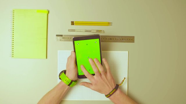 Top view. Green screen. Male hands and typing something in a tablet with a green screen