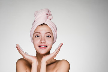 happy girl with a towel on her head on a gray background