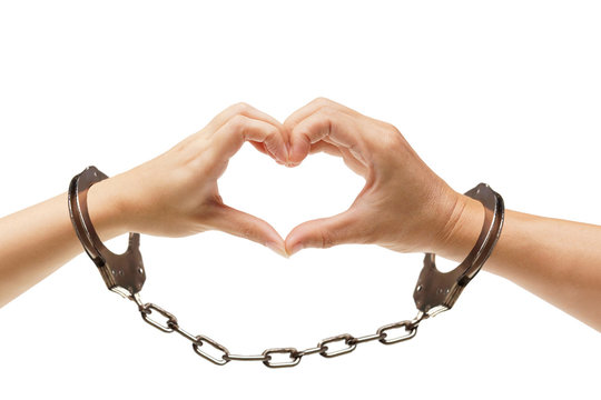 Hands of a couple forming a heart shape with handcuffs / Love and Valentine's day concept