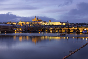 Evening colorful snowy Christmas Prague Lesser Town with gothic Castle and Charles Bridge, Czech republic