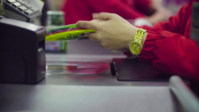 Close up check out counter. Hands of woman working on cash register in the supermarket