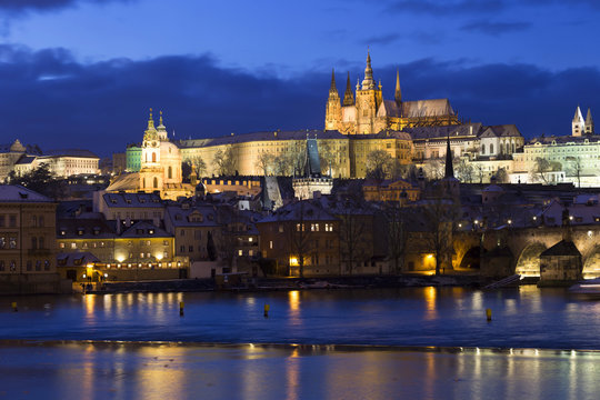 Evening colorful snowy Christmas Prague Lesser Town with gothic Castle and Charles Bridge, Czech republic