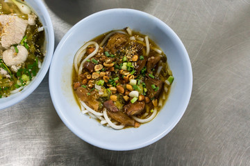 A bowl of Hainan rice noodle with braised beef in Thai style on stainless steel table.